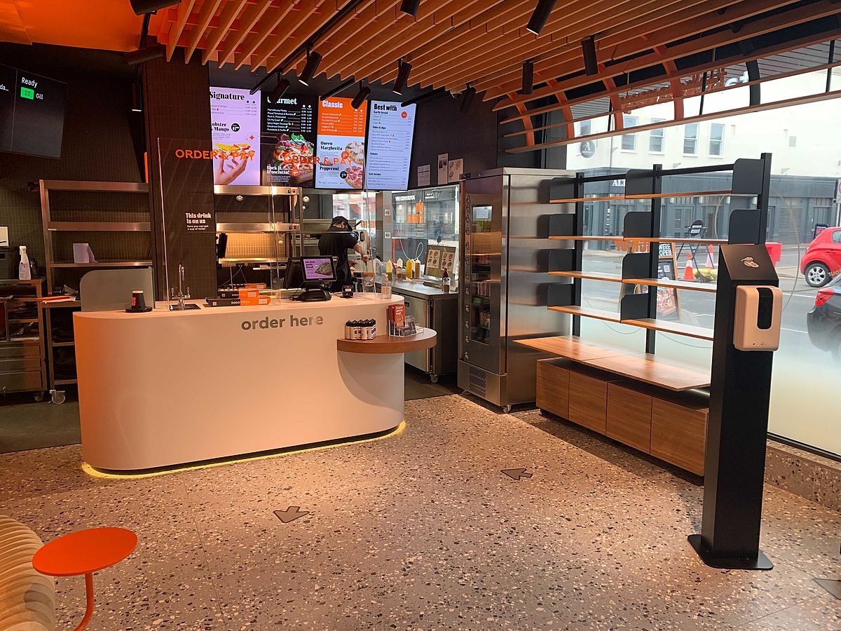 Restaurant interior with the order counter, digital menu boards and a self-service kiosk