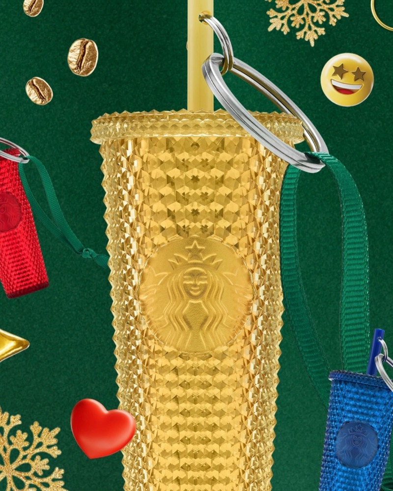 Gold studded cold cup with a strap and charms, on the same green Christmas background