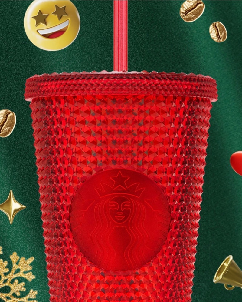 Red studded cold cup with an embossed siren, among coffee beans, snowflakes and a star-eyes emoji