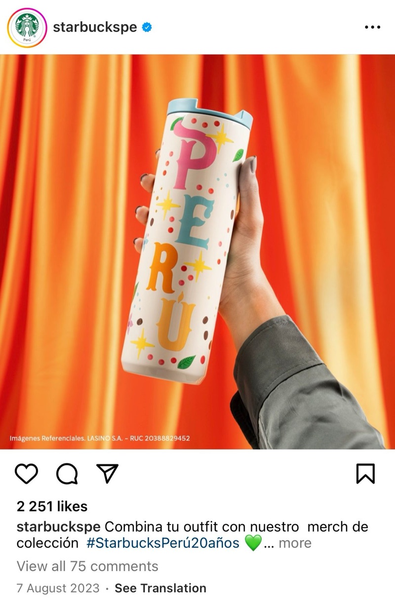 Starbucks Peru Instagram post for its 20th anniversary: a hand holding the Peru tumbler against orange curtains